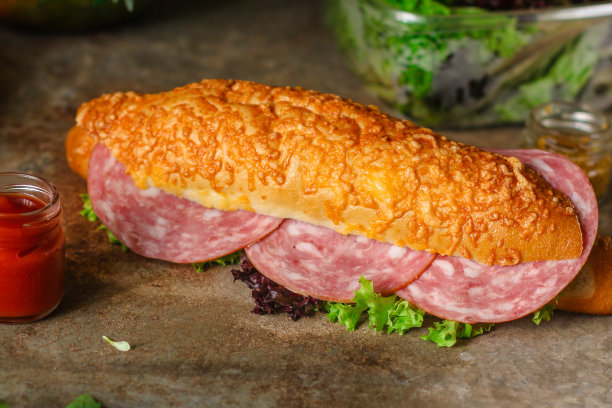 夹有面包卷、生菜、香肠和火腿的三明治，在木制的背景上。野餐的食物。俯视图图片下载