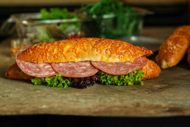 夹有面包卷、生菜、香肠和火腿的三明治，在木制的背景上。野餐的食物。俯视图图片下载