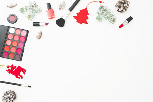 美丽的圣诞书桌与化妆品，配件，装饰品和松果在白色的背景。节日组成。平躺，俯视图。图片下载