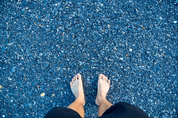 男人的脚踩在蓝色的花岗岩砾石上图片下载