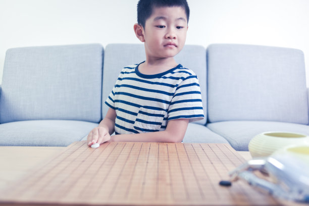 聪明的男孩在室内和机器人玩围棋游戏图片下载