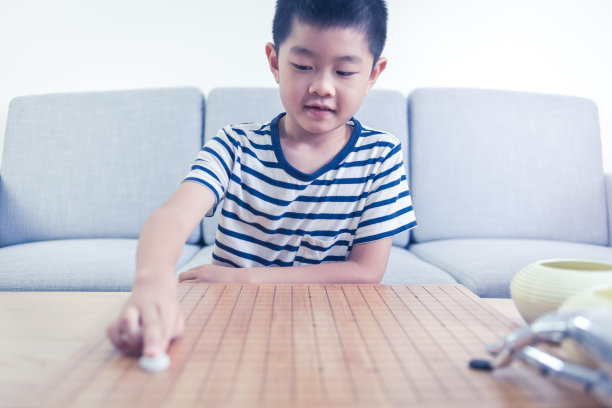 聪明的男孩在室内和机器人玩围棋游戏图片下载