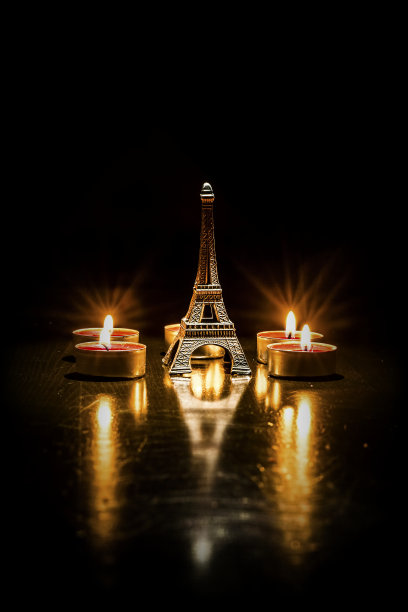 埃菲尔铁塔的背景是五彩缤纷的彩灯花环，散景。埃菲尔铁塔小模型和蜡烛。图片下载