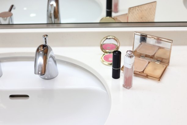 浴室水槽里放着化妆品和智能手机。粉底、口红和腮红图片下载