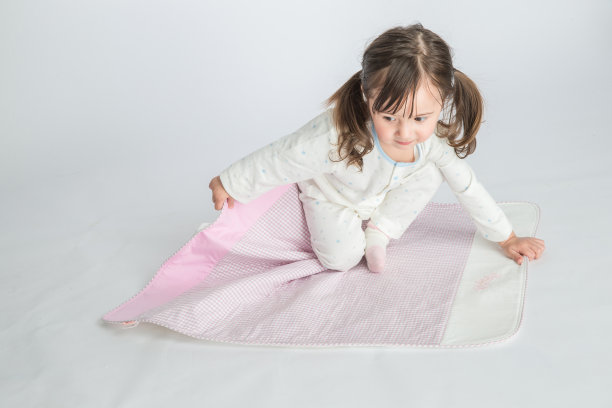 小女孩正坐在粉红色的垫子上图片下载