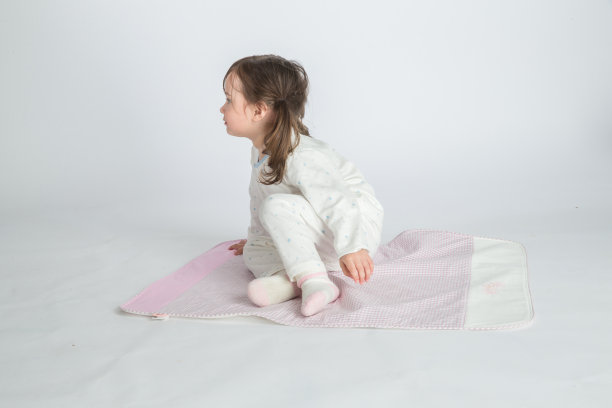小女孩正坐在粉红色的垫子上图片下载
