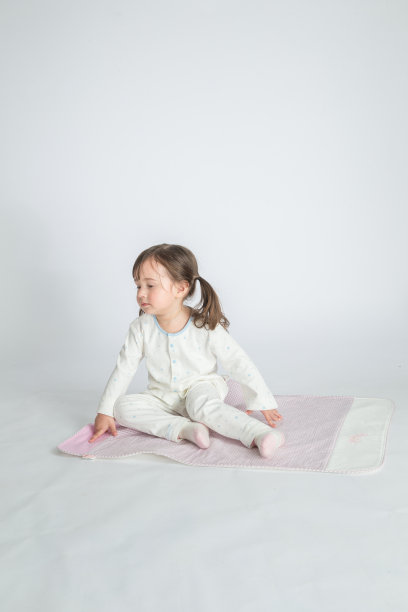 小女孩正坐在粉红色的垫子上图片下载