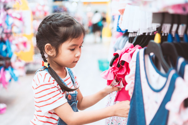 可爱的亚洲小女孩在超市的服装部挑选衣服图片下载