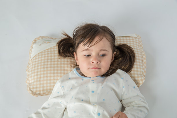 快乐的小女孩在家里的床上有一个枕头图片下载