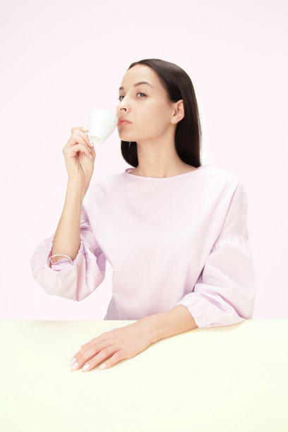 一个美丽孤独的女人坐在演播室手里拿着一杯咖啡，看起来很悲伤。特写镜头的肖像图片下载