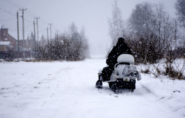 一个人在雪地摩托上。一个骑摩托雪橇的年轻人。在冬天骑雪地摩托。图片下载