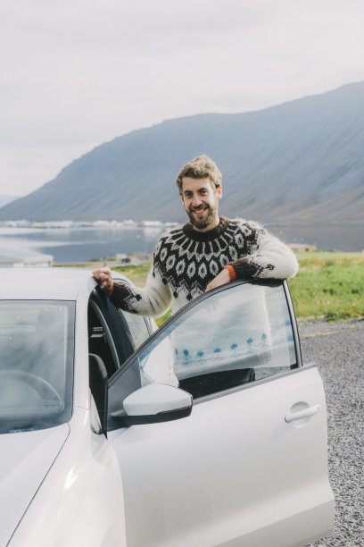 在冰岛，一个穿着冰岛毛衣的男人站在汽车旁边图片下载