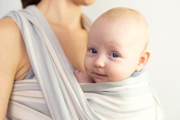 宝宝和妈妈快乐。婴儿在母亲身边用吊带吊着。图片下载