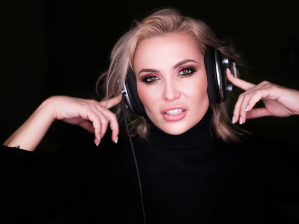 性感的金发女人通过耳机听音乐图片下载