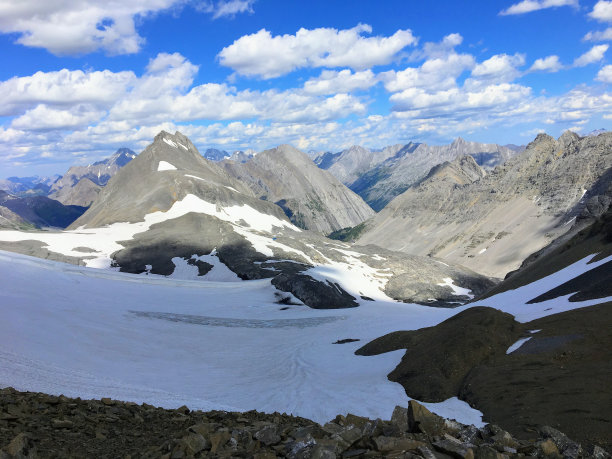 在一个温暖阳光明媚的日子里，在加拿大阿尔伯塔省卡纳纳斯基斯，一个雪谷隐藏在落基山脉的阴影和光秃秃的山峰的背景。图片下载