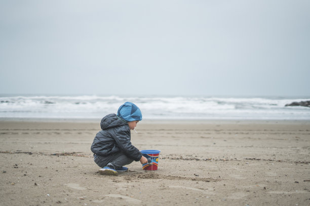 男孩在沙滩上拿着沙桶图片下载
