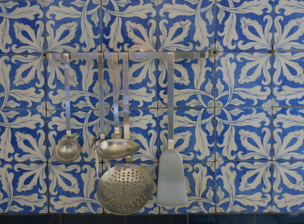 旧金属厨具挂在古老的厨房瓷砖墙上，上面有花的图案图片下载