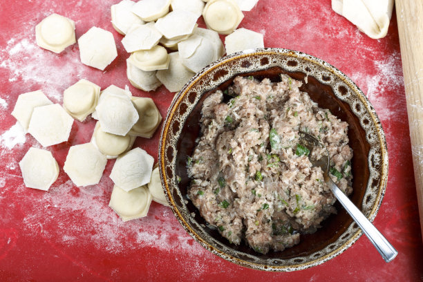 肉馅和饺子放在桌上用面粉。图片下载