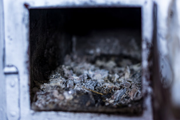 一个木材燃烧炉的门的特写。锻造铁饰品和灰。冬天家的温馨，在寒冷的冬天里温暖。图片下载