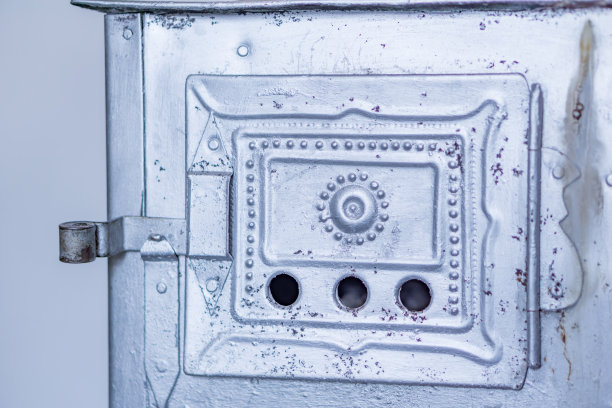 一个木材燃烧炉的门的特写。锻造铁饰品和灰。冬天家的温馨，在寒冷的冬天里温暖。图片下载