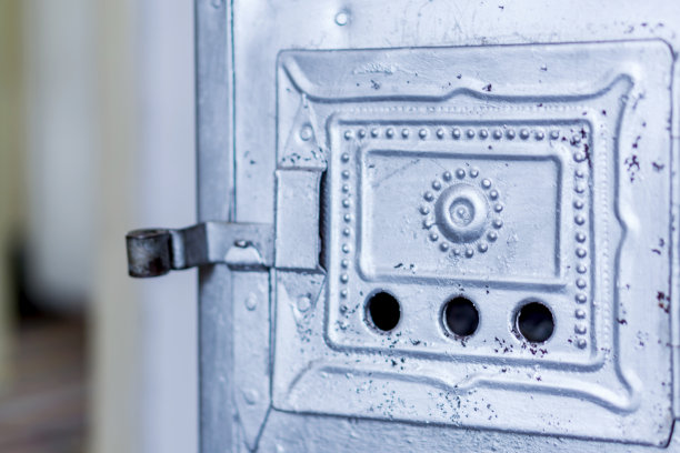 一个木材燃烧炉的门的特写。锻造铁饰品和灰。冬天家的温馨，在寒冷的冬天里温暖。图片下载