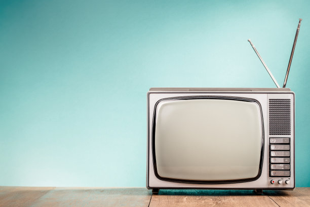 复古的老式电视接收器放在桌子前面渐变的海蓝宝石墙背景上。复古风格滤镜照片图片下载