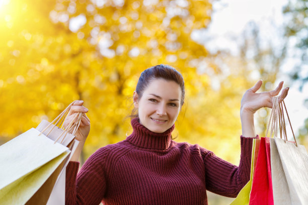 一个面带微笑的女人把买的东西抱在怀里。图片下载