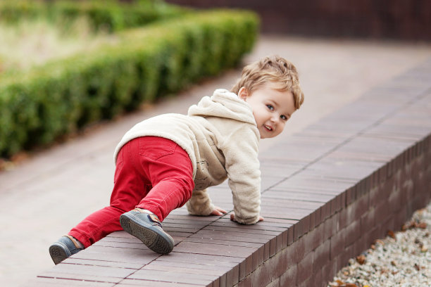 小男孩微笑着在公园里爬行。可爱的孩子的微笑和快乐。儿童户外活动图片下载