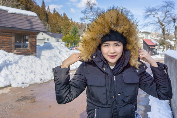 年轻的亚洲女性第一次享受大雪。冬天年轻的亚洲女人肖像在雪冬天的时间。图片下载