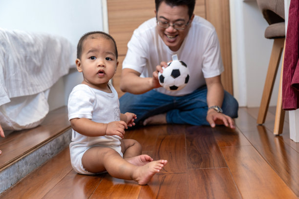 亚洲男婴在卧室木地板上爬行，父母在旁图片下载