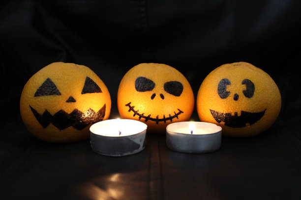 万圣节的概念。有趣的橙色橘子或橘子，南瓜画在形式的万圣节的图标在黑色的背景。万圣节的时候画的可怕的脸。图片下载