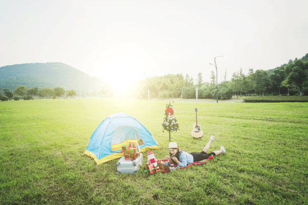 在秋天的黄昏，一个年轻的亚洲女子在草地上用手机摆拍自己的照片，在一个日落的圣诞户外派对上。图片下载
