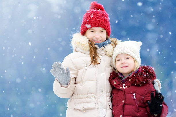 两个可爱的小女孩在美丽的冬季公园一起玩。美丽的姐妹们在雪地里玩耍。图片下载
