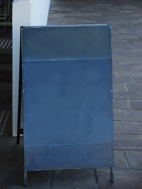 在城市的人行道上，楼梯旁的空白黑板上的文字被严重擦除。图片下载