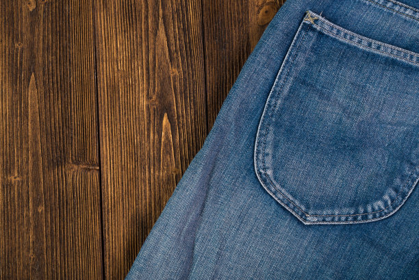 磨损牛仔裤或蓝色牛仔裤牛仔收集在粗糙的深色木制桌子背景，顶部视图与拷贝空间，旧的时尚概念。图片下载