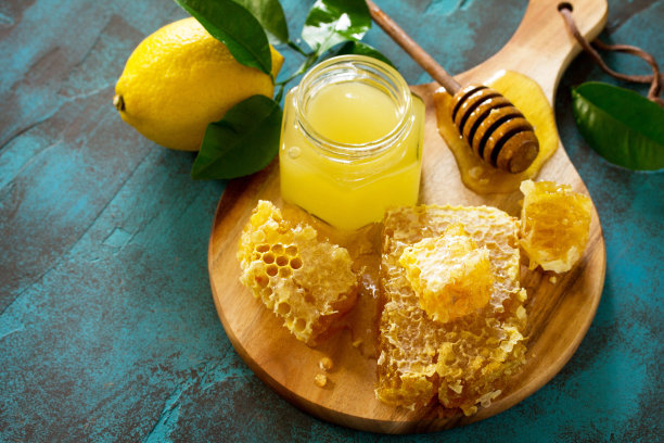 天然蜂蜜加柠檬。蜂蜜在玻璃罐和勺子，甜蜜的蜂蜜在青石桌上。本空间图片下载