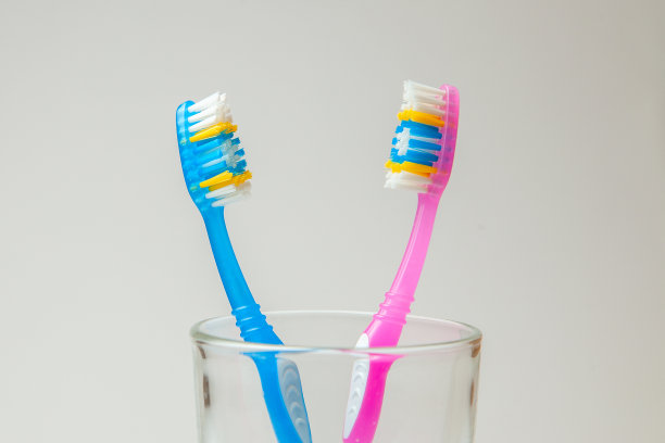两颗玻璃假牙，灰色背景，粉色和蓝色。夫妻牙刷的概念，共同居住作为家庭的开始图片下载