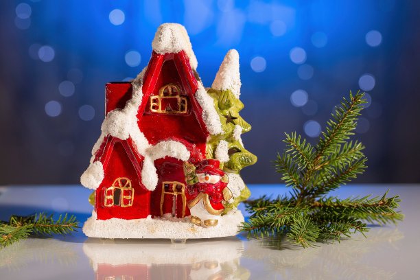 装饰可爱的红色房子与圣诞树在蓝色闪闪发光的背景。圣诞节/新年美丽的背景。图片下载