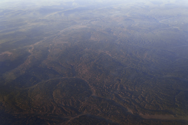 从飞机的窗口观看地平线上的湖泊和河流与森林在日落的一天被太阳光线图片下载
