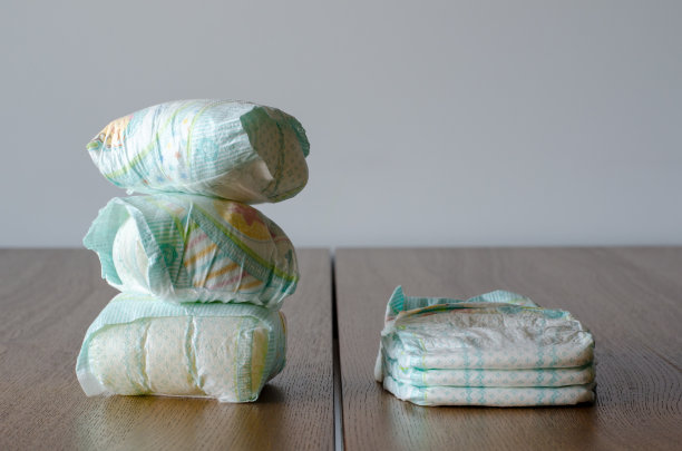 木桌背景上放着新的和用过的婴儿尿布。图片下载