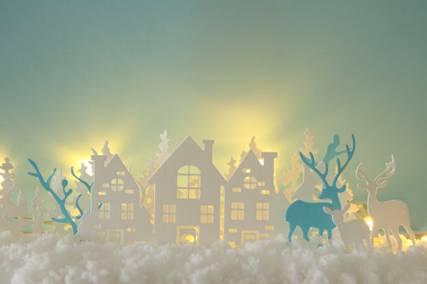 神奇的圣诞剪纸冬天的背景景观与房子，树，鹿和雪前面的金色灯光背景。图片下载