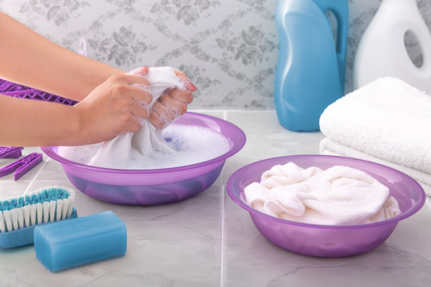 一个妇女用肥皂水手洗衣服。图片下载