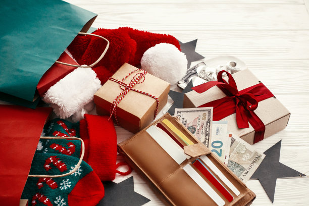 圣诞购物和销售概念。钱包里的信用卡和钱，装衣服的纸袋，袜子，礼品盒，白色乡村背景上的珠宝。季节性广告和销售图片下载