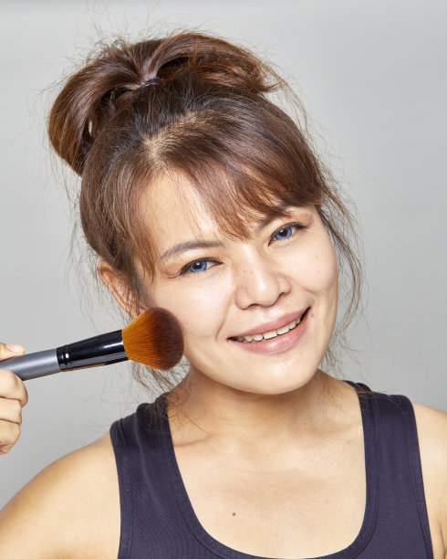 年轻美丽的女人与化妆刷孤立在白色的背景图片下载