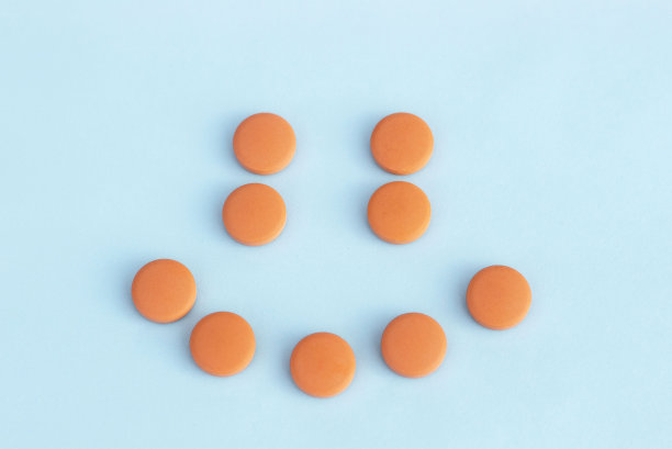 蓝色背景下橙色药丸的微笑。抗抑郁药的概念图片下载