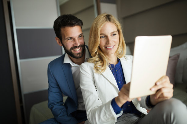 商人和女商人坐在床上使用平板电脑图片下载