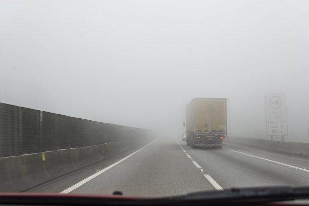 一辆卡车在浓雾中在双车道上超车。图片下载