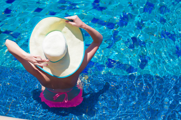 戴着大帽子的年轻女子在游泳池里放松图片下载