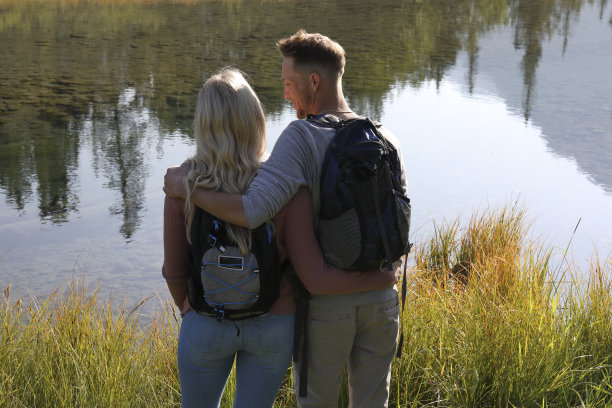 年轻的徒步夫妇驻足在小溪边，森林倒影图片下载