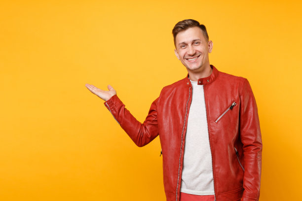 肖像时尚微笑帅气的年轻人25-30岁身穿红色皮夹克，t恤孤立地站在明亮的趋势黄色背景上。人真诚情感生活理念。广告区域。图片下载